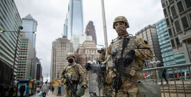 Two National Guard soldiers stand guard in an urban setting