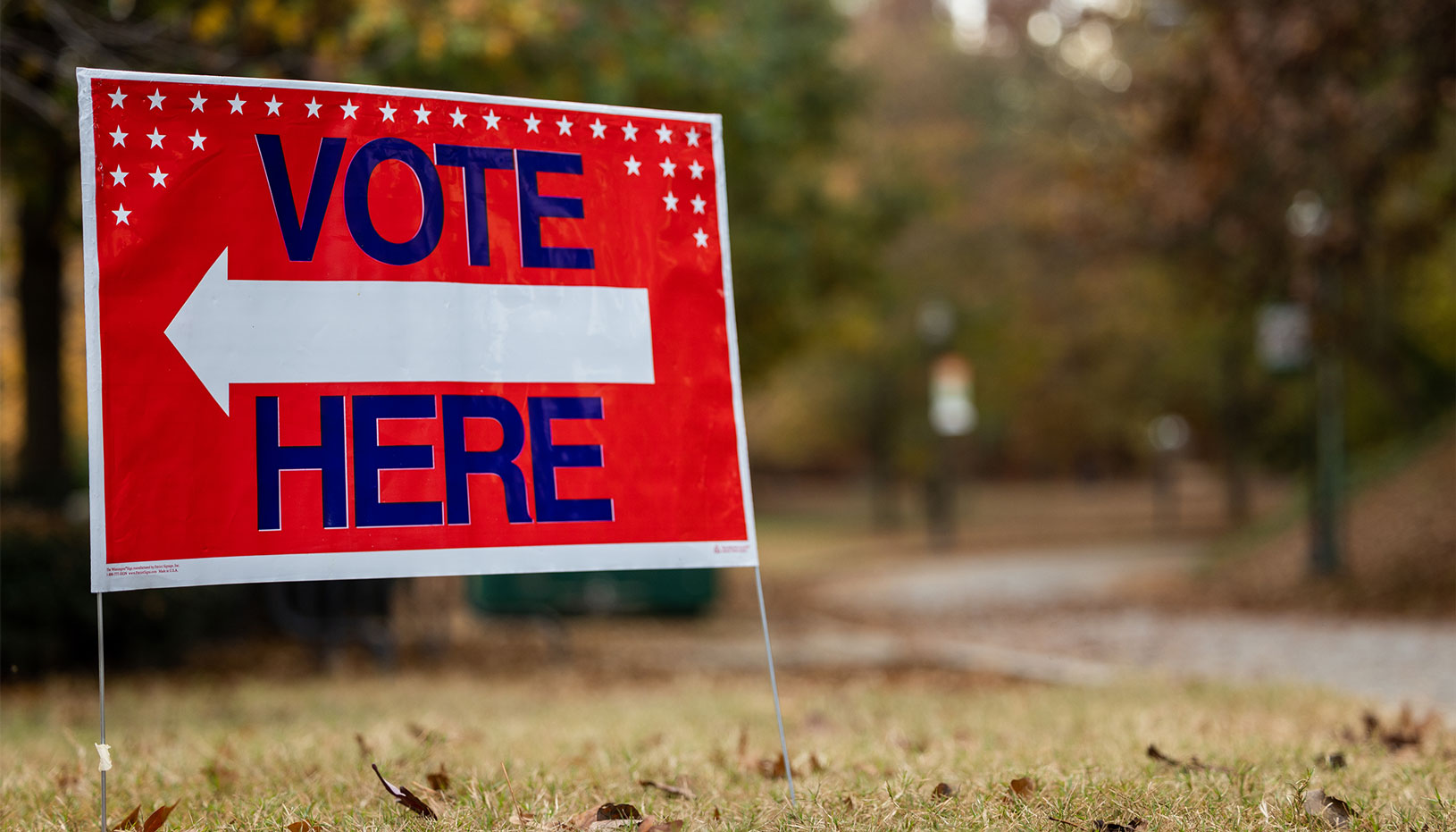 Red sign that has vote here text with white arrow