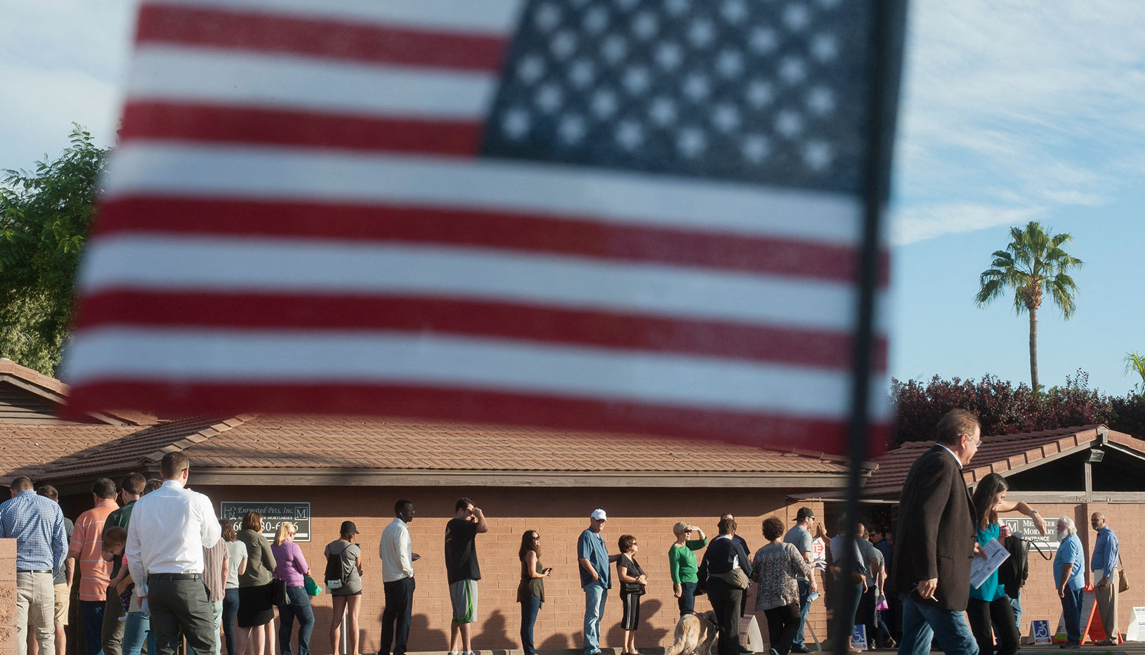 Voters in line with American flag in foreground