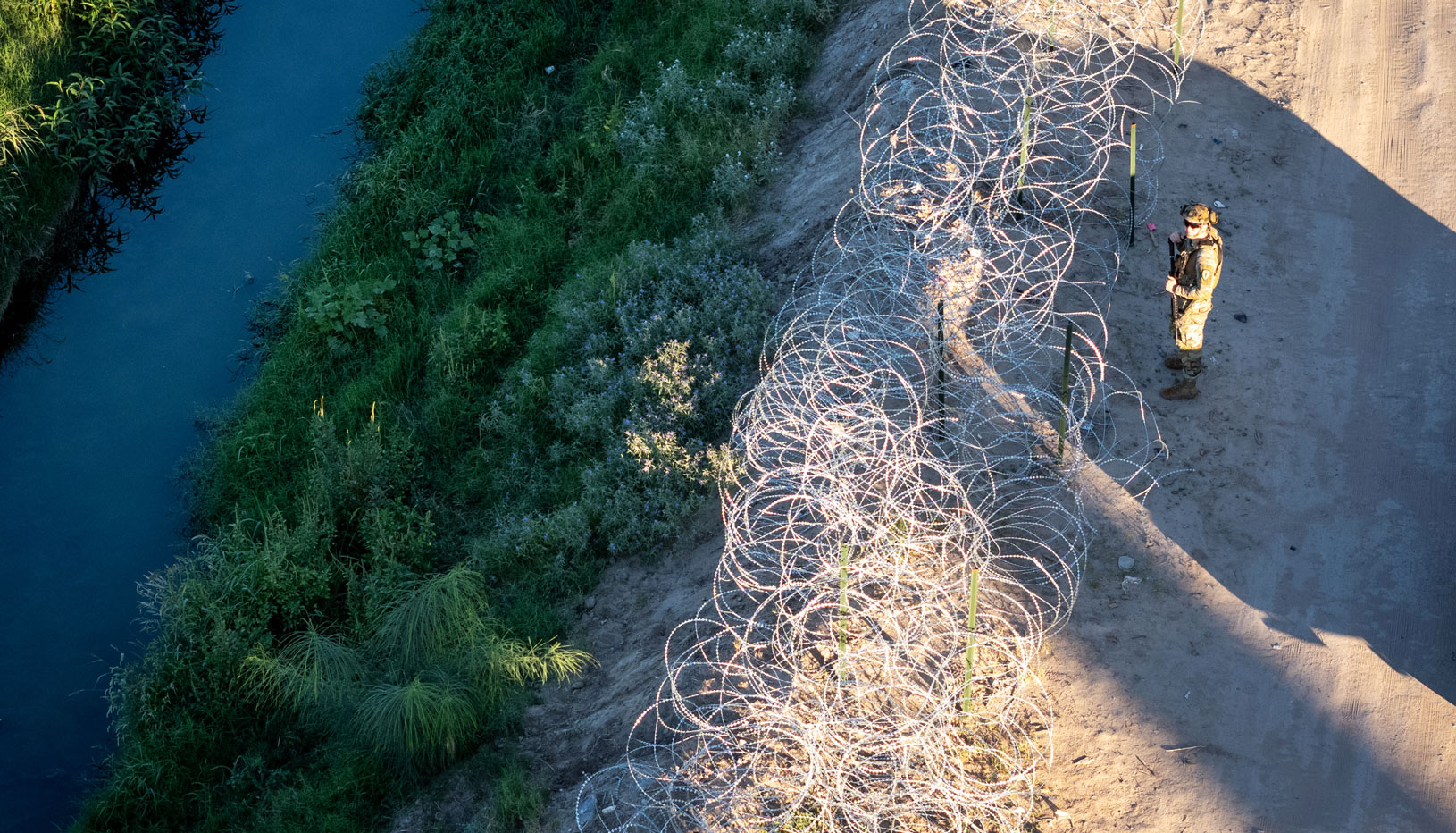 A US troop stands at a barbed wire fence on the US-Mexico border