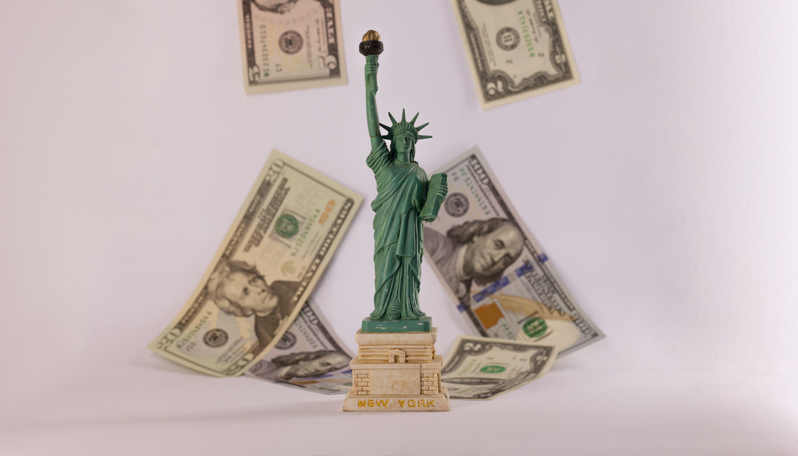 Model Statute of Liberty foreground, cash in background