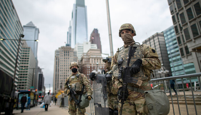 Two National Guard soldiers stand guard in an urban setting