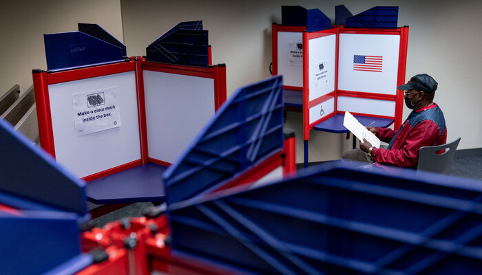 Man filling out voting ballot behind divider