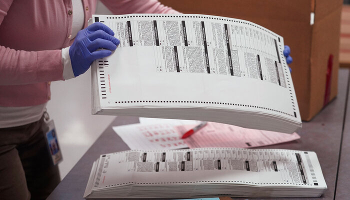 election official handling ballots with gloves