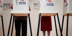 People standing behind a voting booth